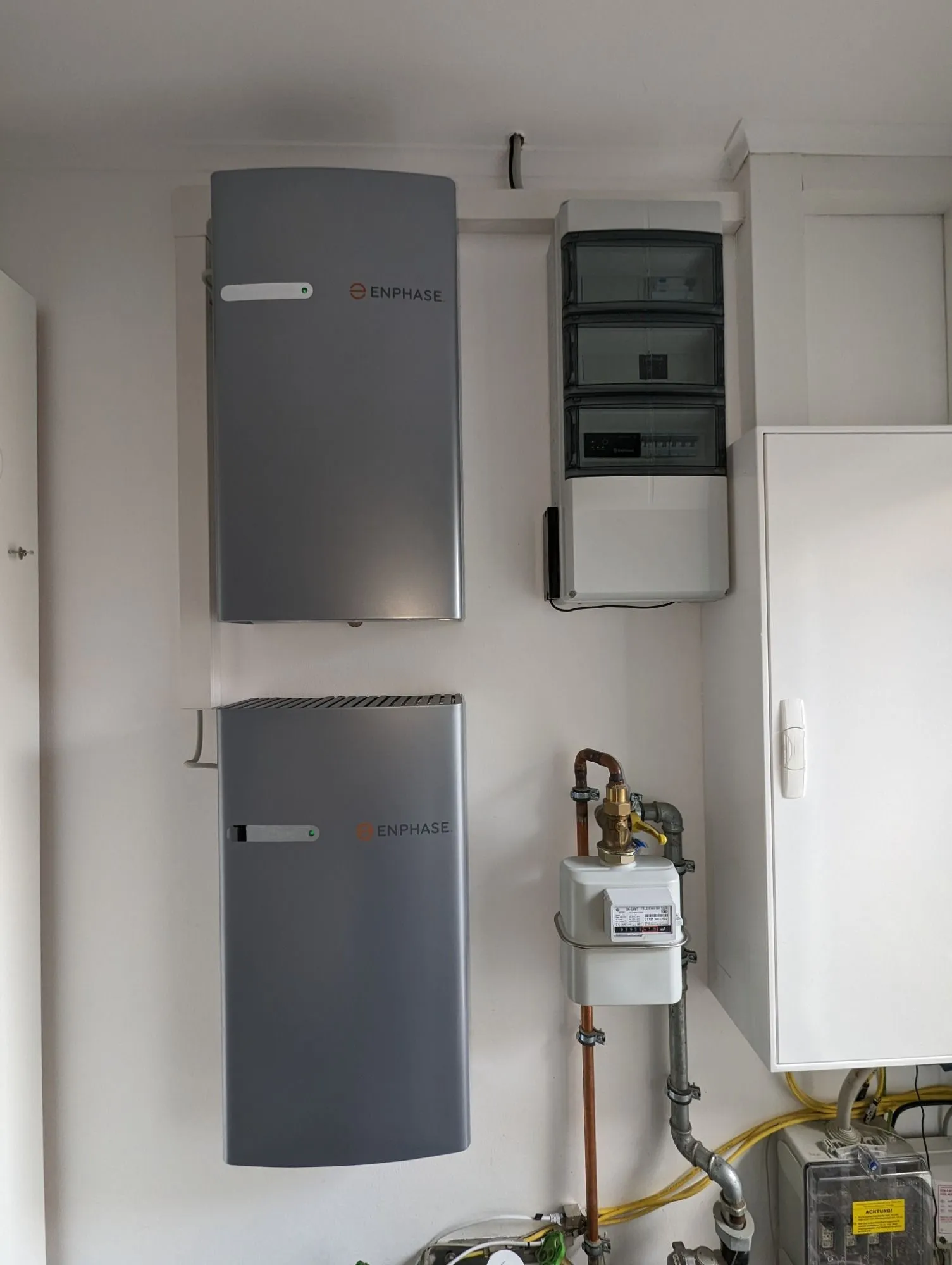 Zwei wandmontierte Batteriespeicher neben Wechselrichter und Zählerschrank