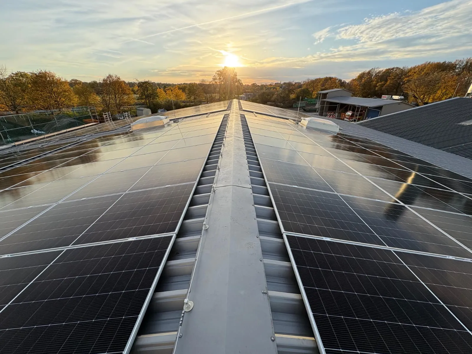 Vollflächig mit Photovoltaik belegtes Hallendach eines Bauhofs, Blick über den First in die tief stehende Sonne